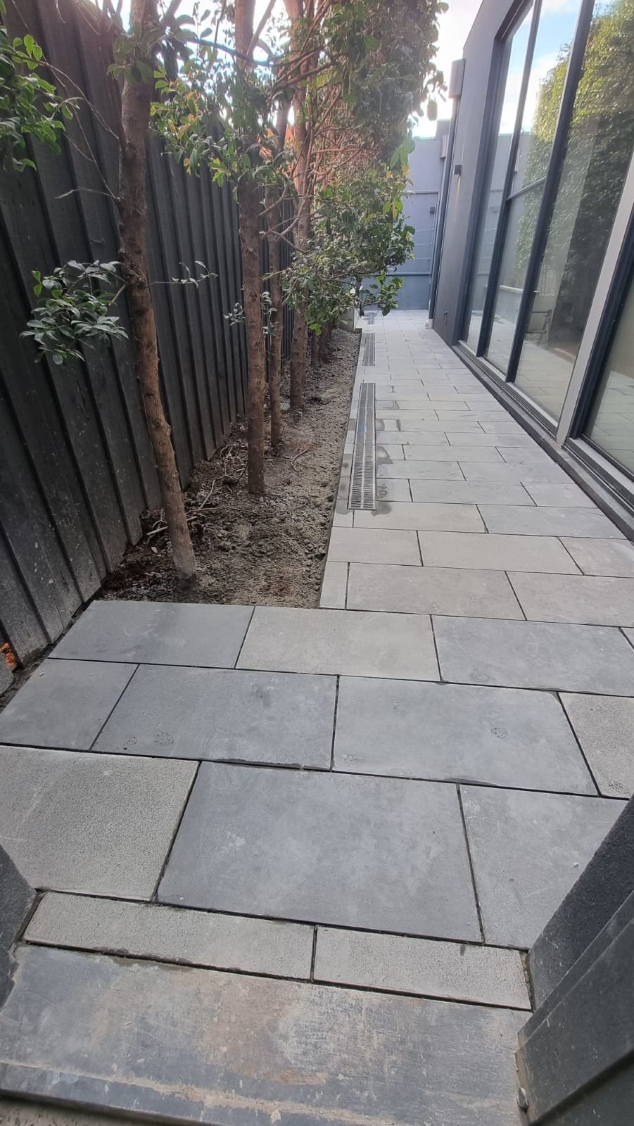 Bluestone side path with stainless strip drain along a modern Melbourne home