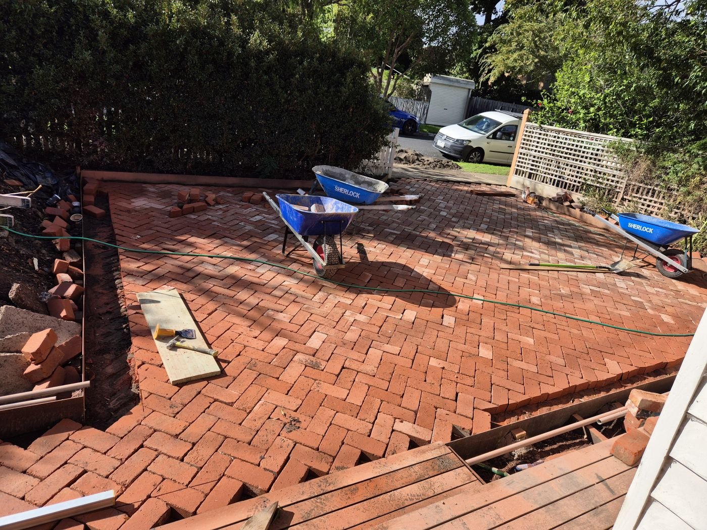 Red brick herringbone paving with a soldier-course edge being completed