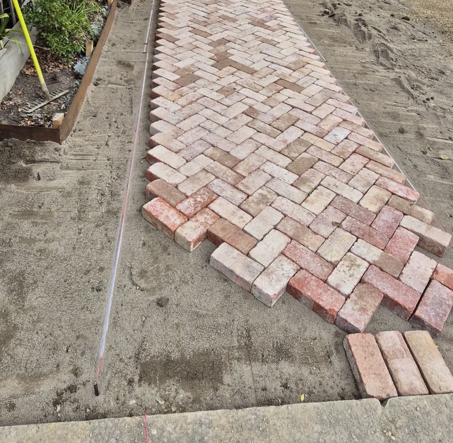 Recycled bricks being laid in herringbone on a screeded sand bed