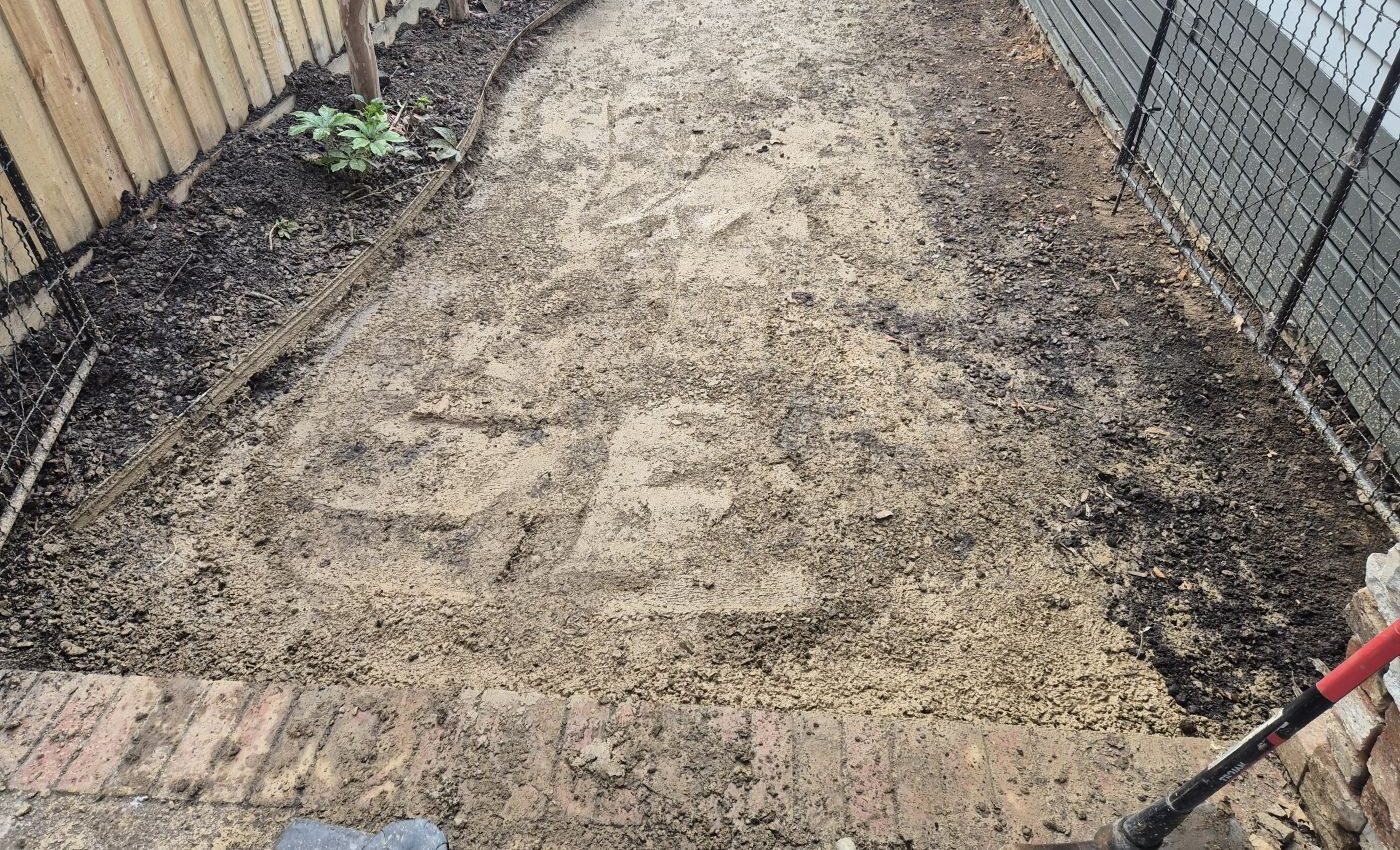 Compacted and screeded base prepared for paving along a garden path