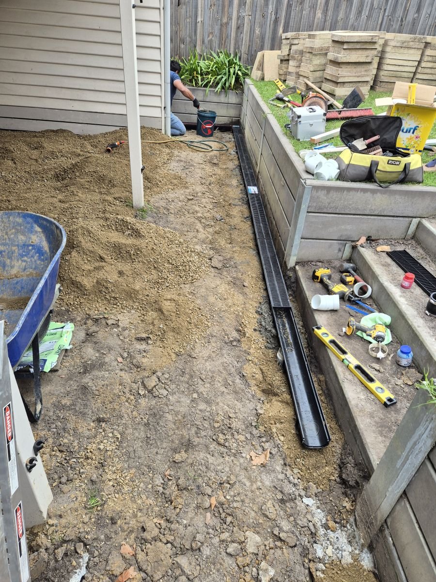Drainage channel being installed along a raised garden bed retaining wall