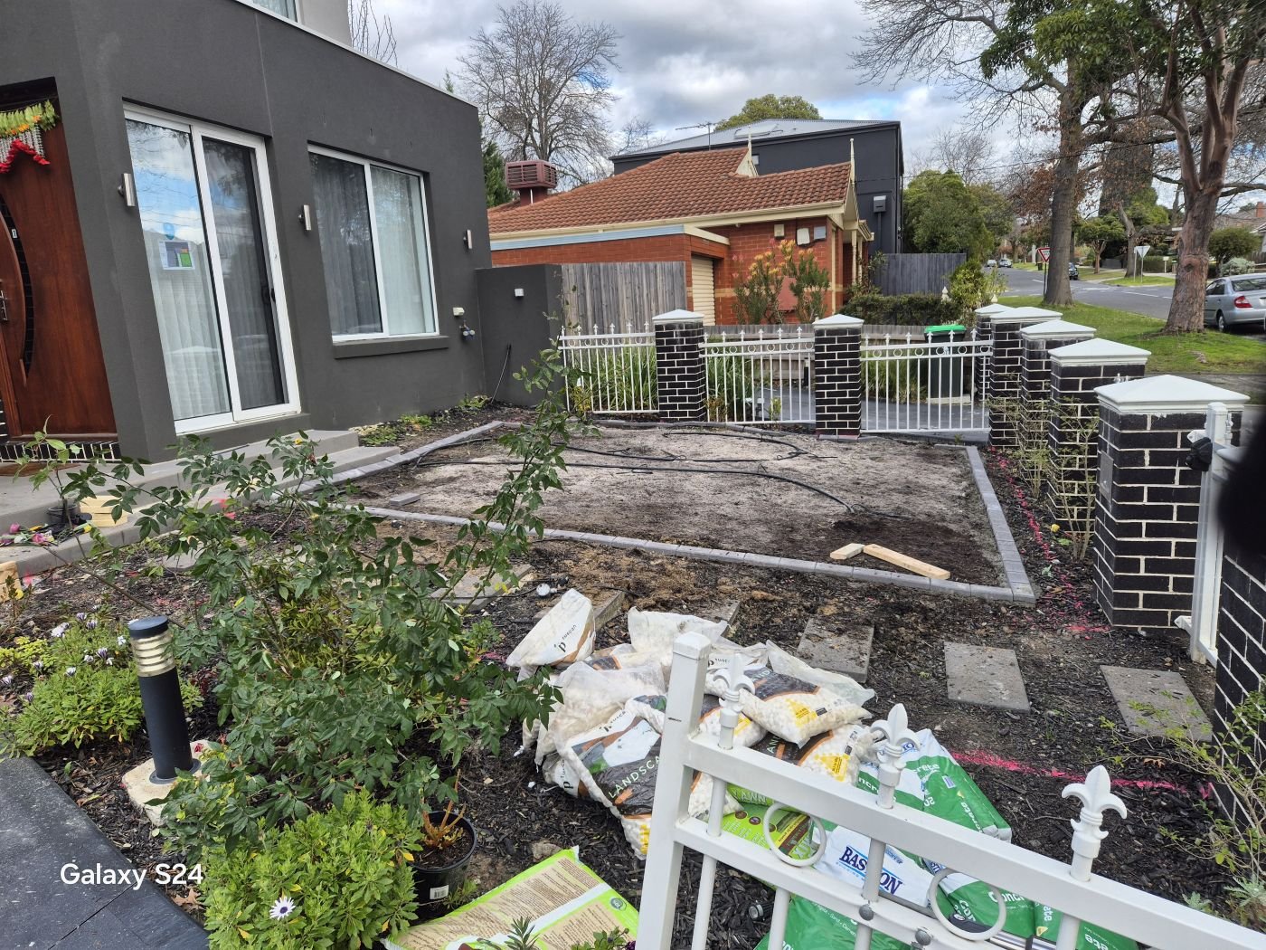 Townhouse front yard before landscaping, bare soil and materials on site