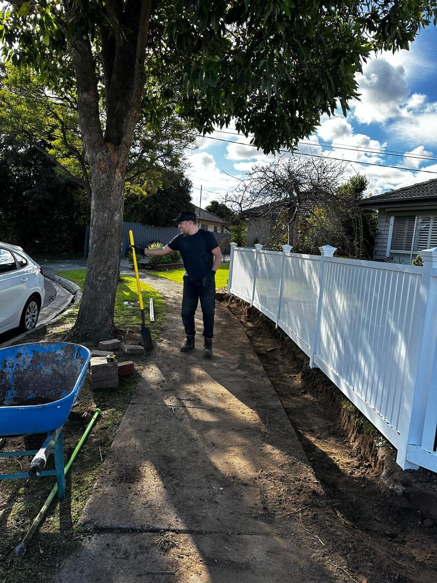 Brick edging being installed along a picket fence