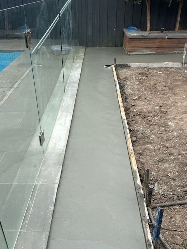 Fresh concrete base poured along frameless glass pool fencing