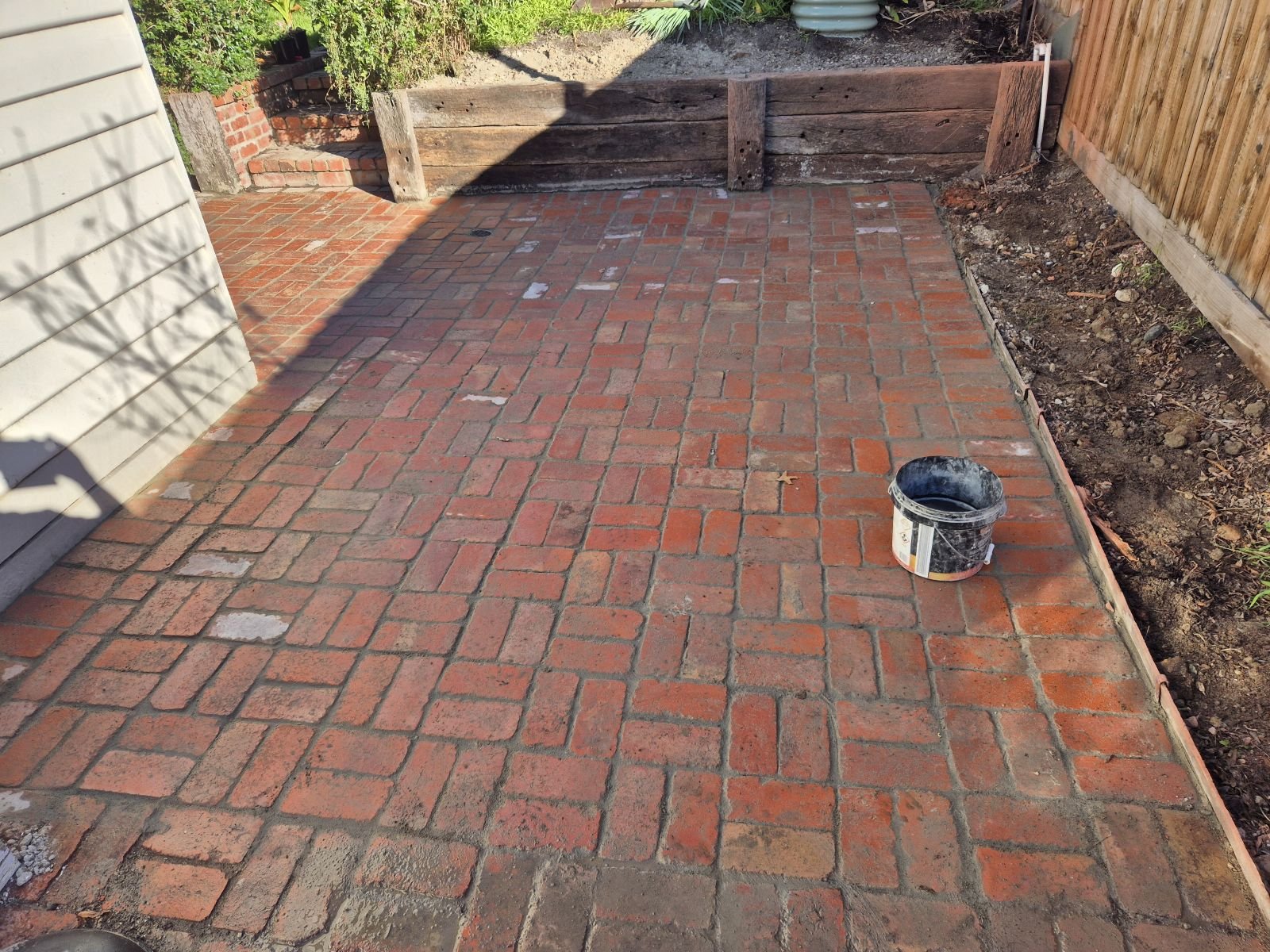 Red brick patio with timber sleeper retaining wall