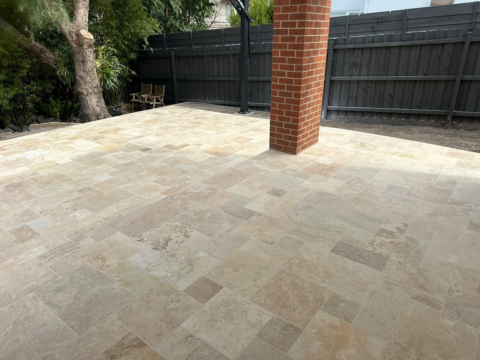 Finished travertine alfresco and garden terrace around a brick pier at a Melbourne home