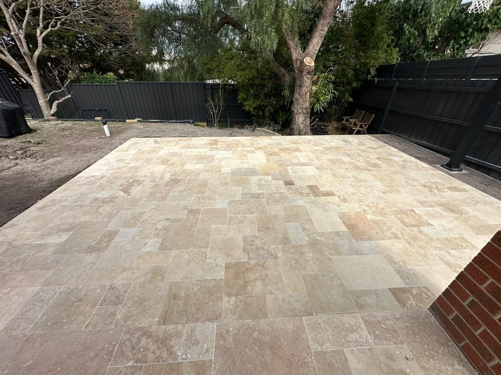 New travertine alfresco laid in a French pattern beside a brick home in Melbourne