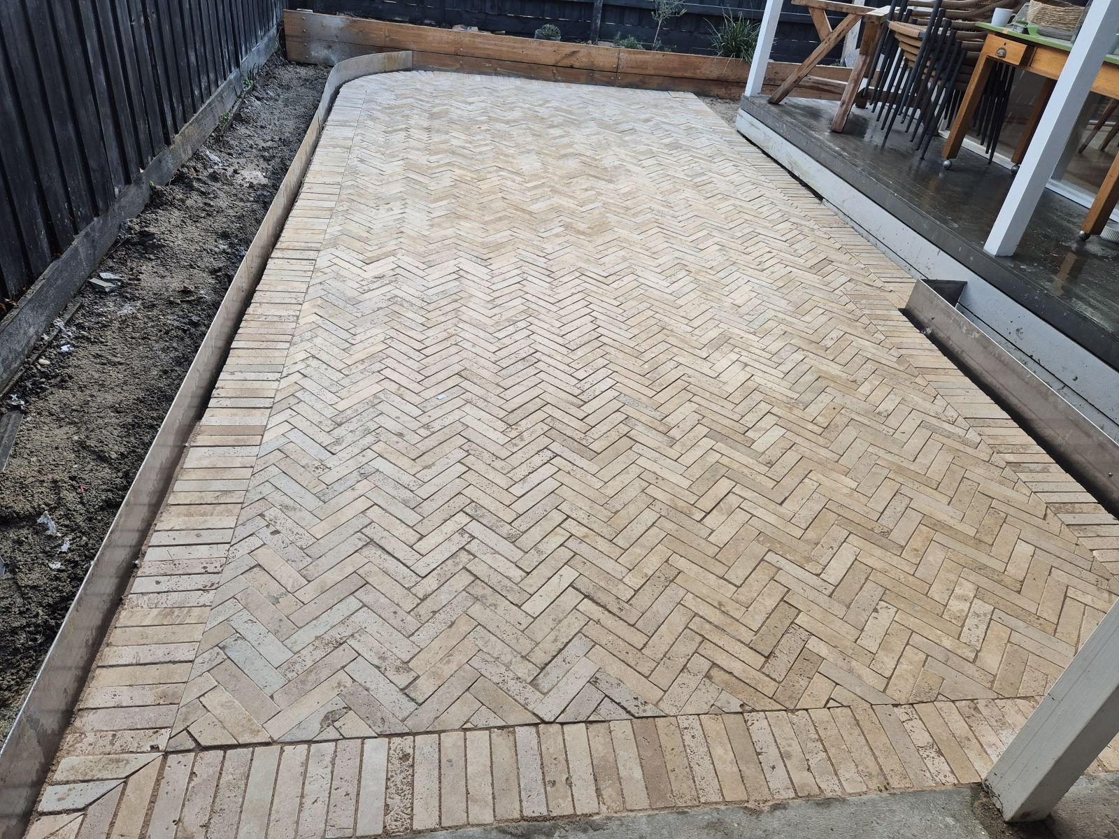 Tumbled paver herringbone patio with timber edging beside an alfresco in Melbourne